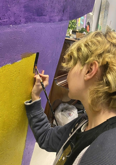 Ung som maler med pensel på kunst installation.