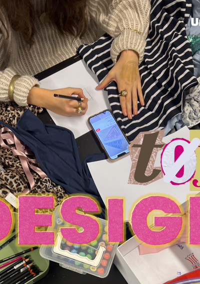 På billedet ses en af pigerne på designholdet, imens hun sidder og skitser hendes næste projekt omringet af stof og sy-grej.