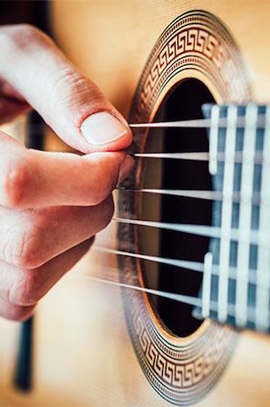 En hånd på en akustisk guitar